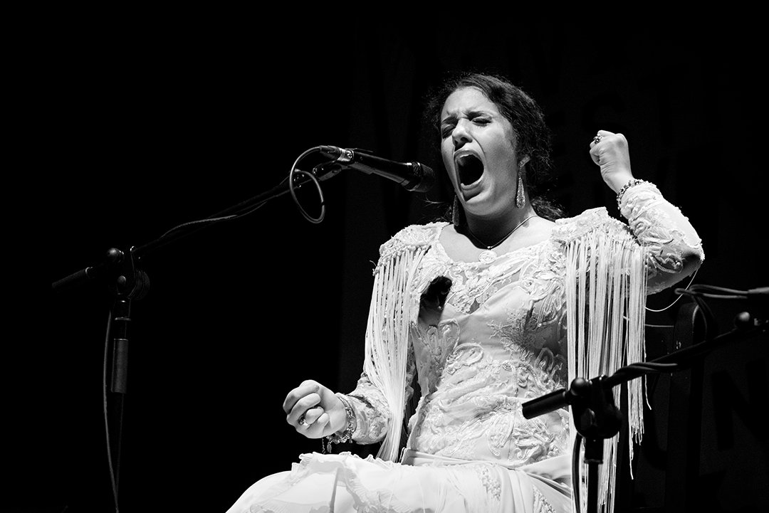 Una cantante canta con una mano alzada.